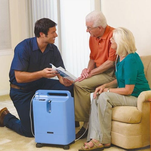 Home care technician explaining Philips EverFlo oxygen concentrator use to an elderly couple